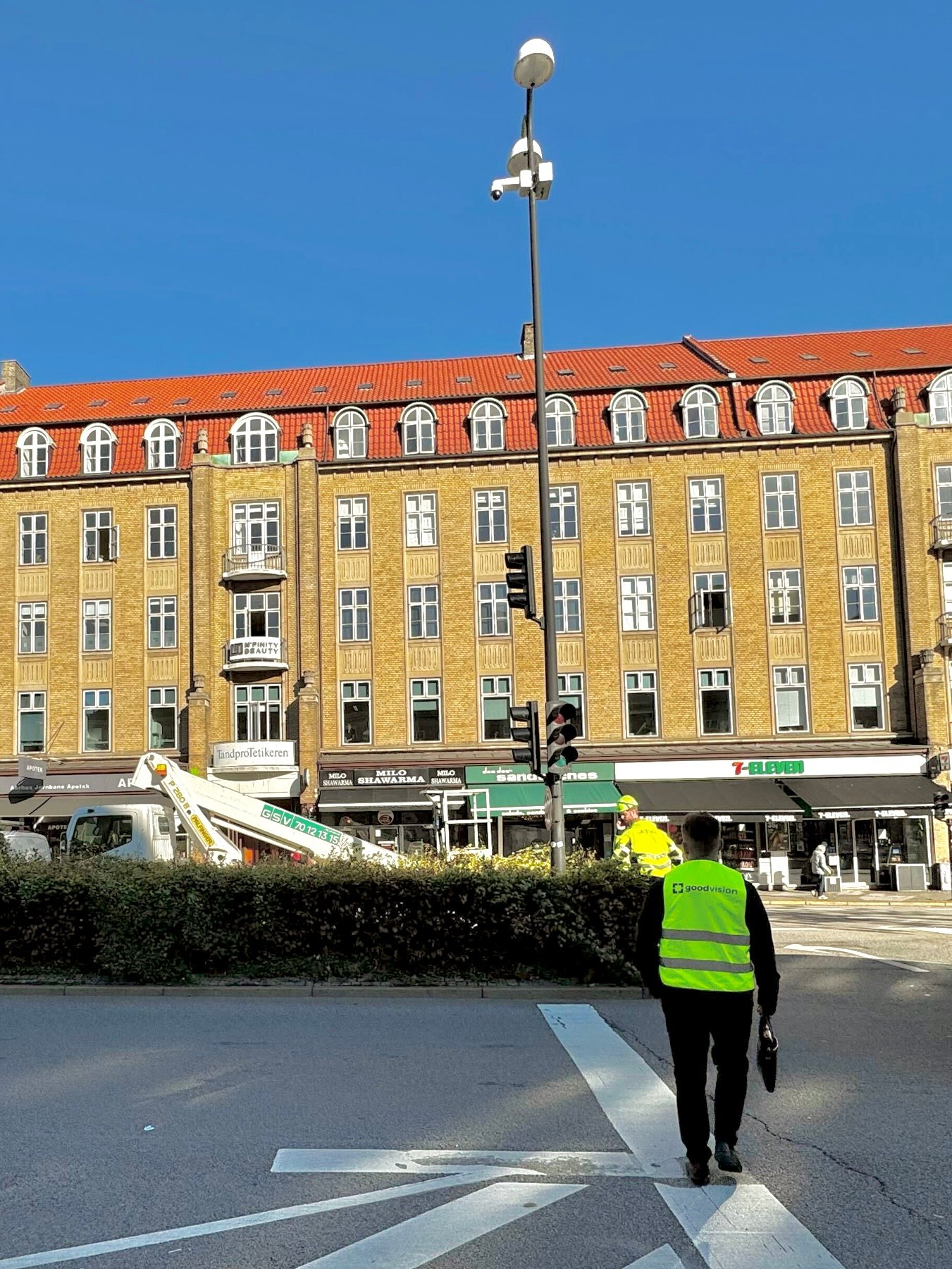 GoodVision software engineer inspecting completed AI parking monitoring installation in Aarhus city center with camera pole and historic Danish architecture