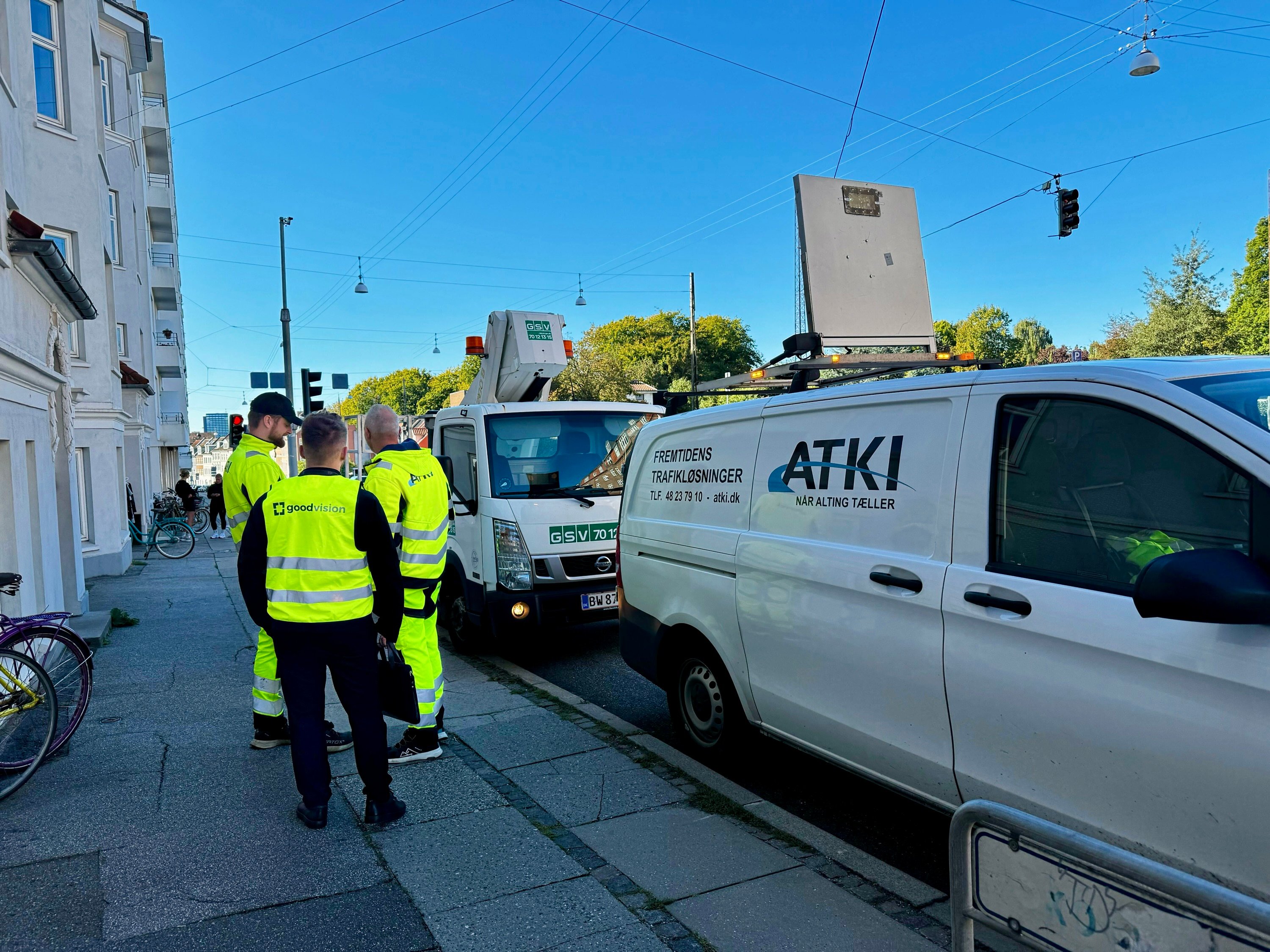 GoodVision software engineers in high-visibility vests coordinate with ATKI Denmark team next to deployment van for AI parking monitoring installation in Aarhus