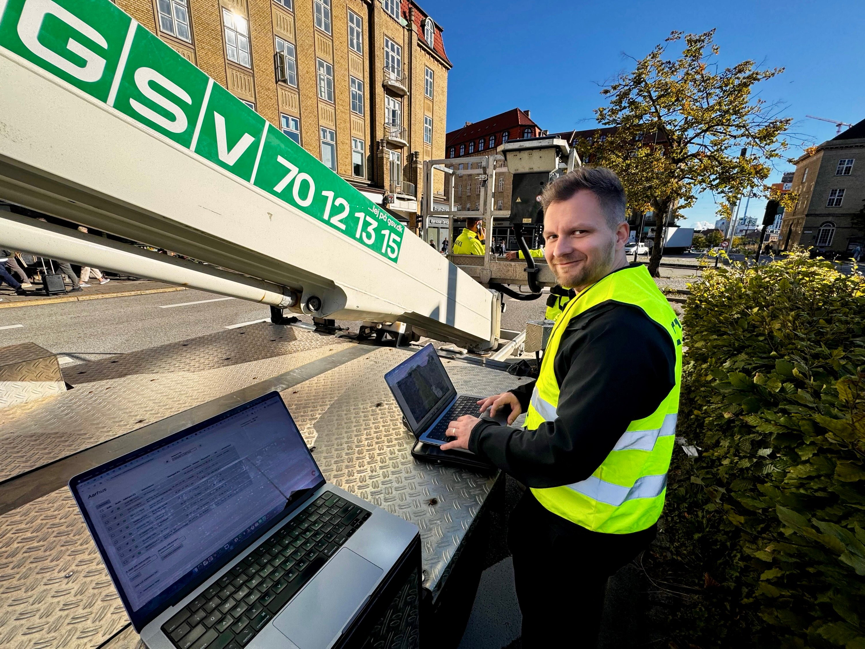 GoodVision software engineer configuring AI-powered parking monitoring system on-site in Aarhus Train Station area with multiple laptops showing real-time data